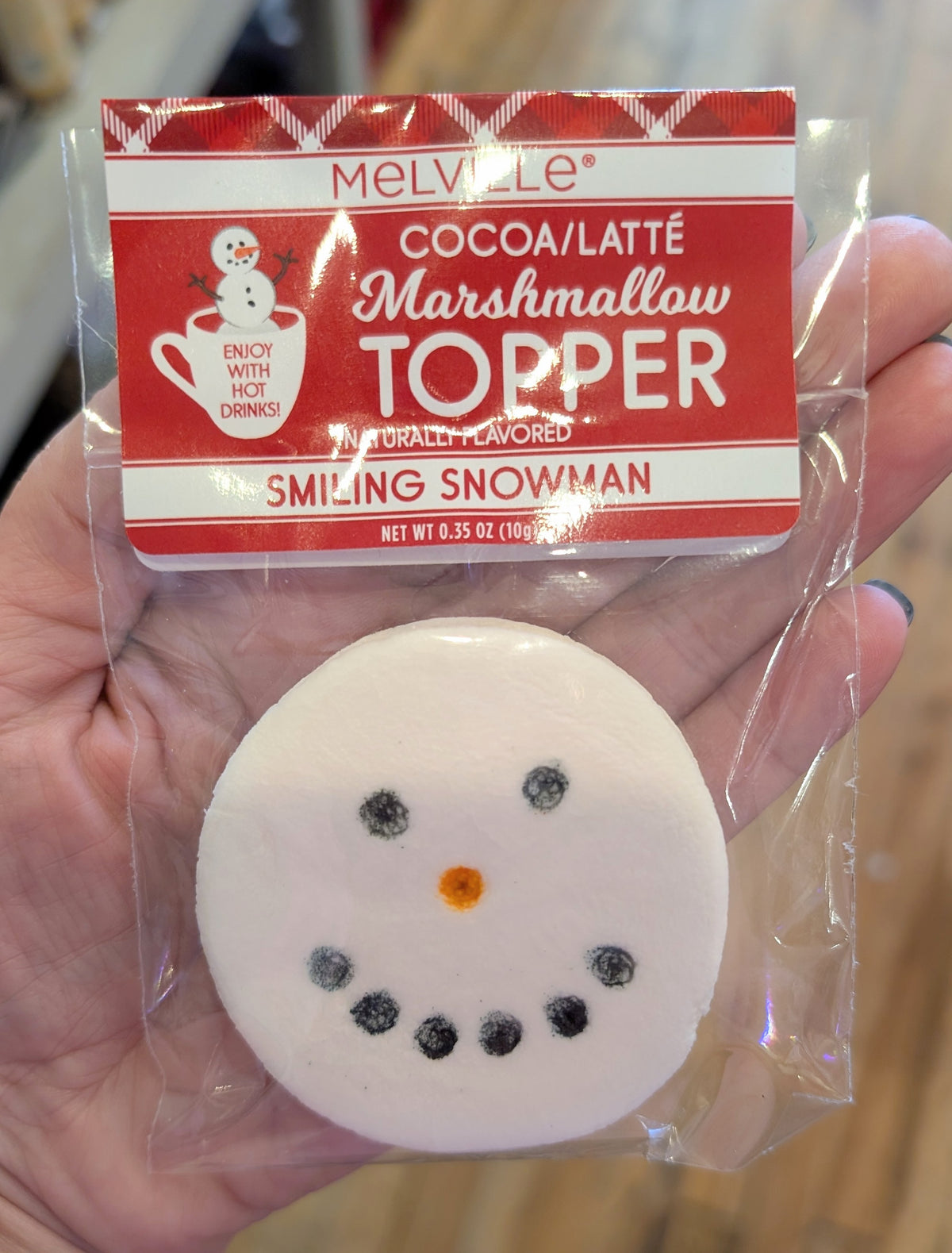 Melville Smiling Snowman marshmallow topper with black candy eyes, an orange nose, and a dotted smile, shown in clear packaging